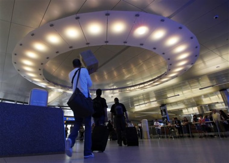 Bathed in blue light from an illuminated wall, not shown, arriving passengers pass under a large “halo” of light in the area where they meet friends and family, at the newly-renovated customs clearance area at the Tom Bradley International Terminal at LAX.